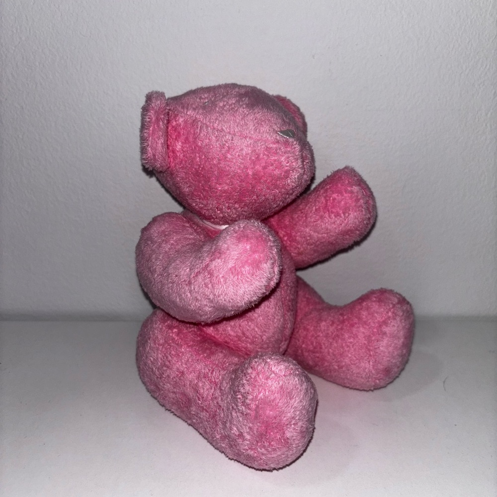 Adorable hot pink Gucci stuffed bear with white Gucci lettering on leg